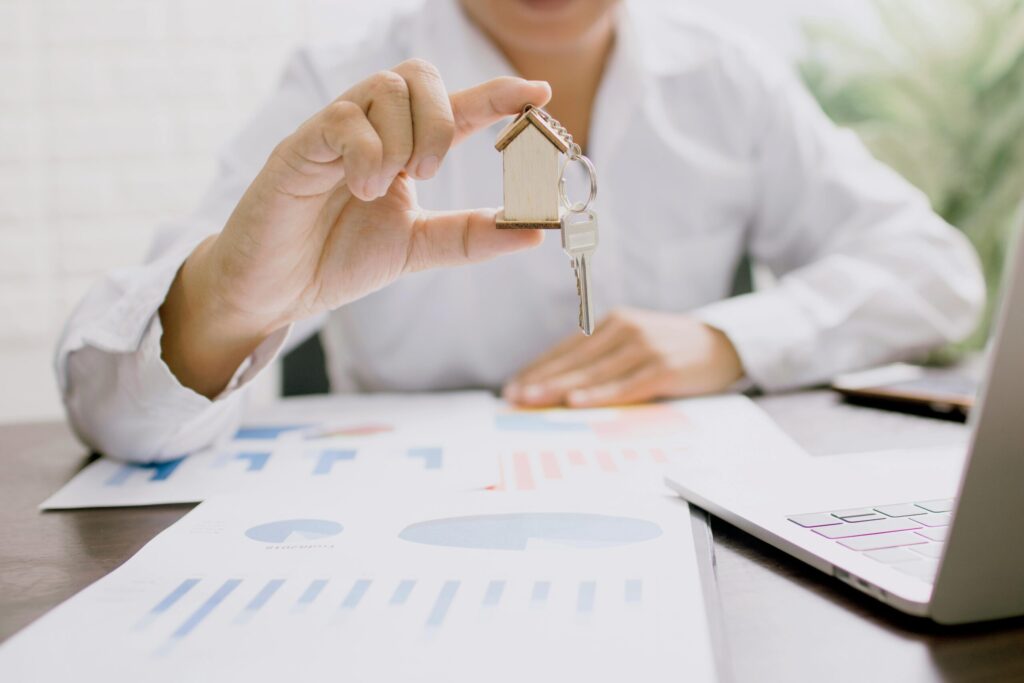 a man in white long sleeve shirt holding a key with a house keychain