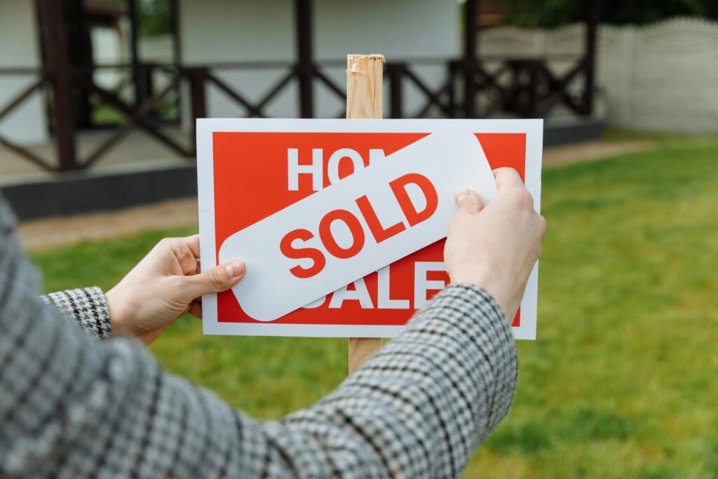 a realtor posting a sold sticker to a sign