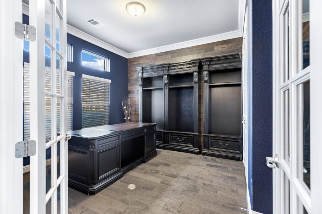 a home office featuring a dark wood executive desk and matching built-in shelving