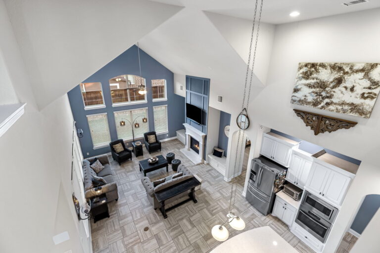 a modern open-concept residential interior, specifically a living room with a high, vaulted ceiling and an attached kitchen