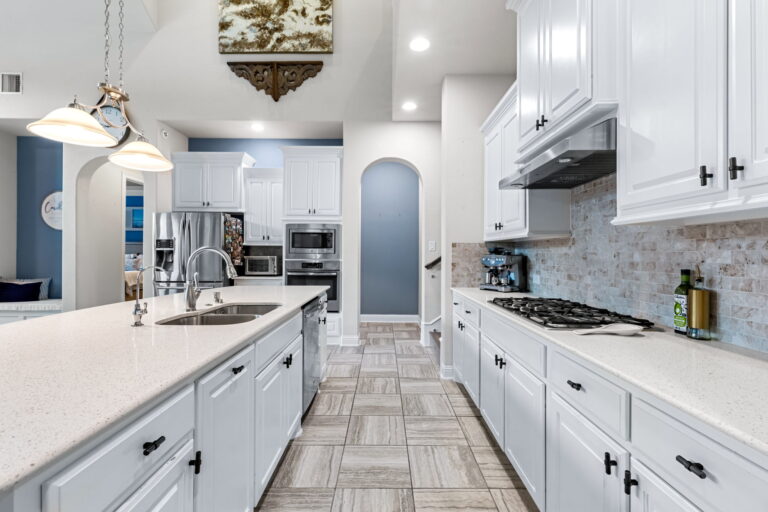 a modern kitchen featuring white cabinets with dark hardware and light-colored countertops.