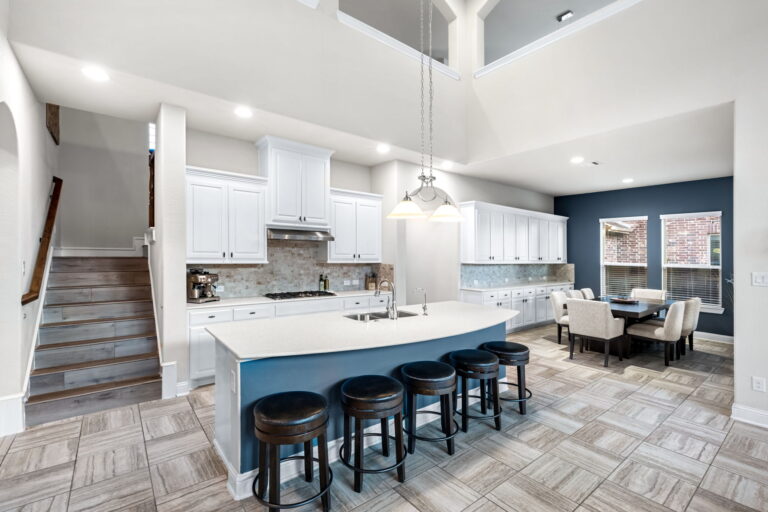 a modern kitchen featuring white cabinets with dark hardware and light-colored countertops.