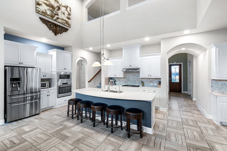 a modern open-concept residential interior, specifically a living room with a high, vaulted ceiling and an attached kitchen