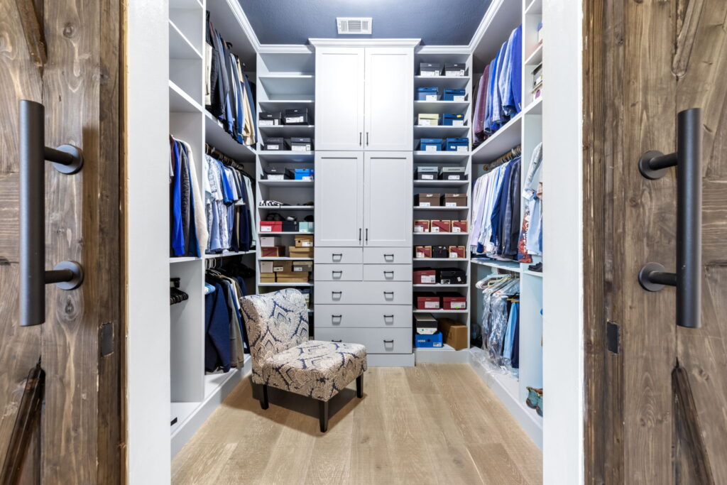 a custom master walk-in closet designed with built-in white cabinetry
