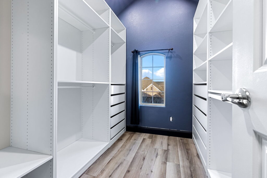 a modern walk-in closet featuring white built-in shelving