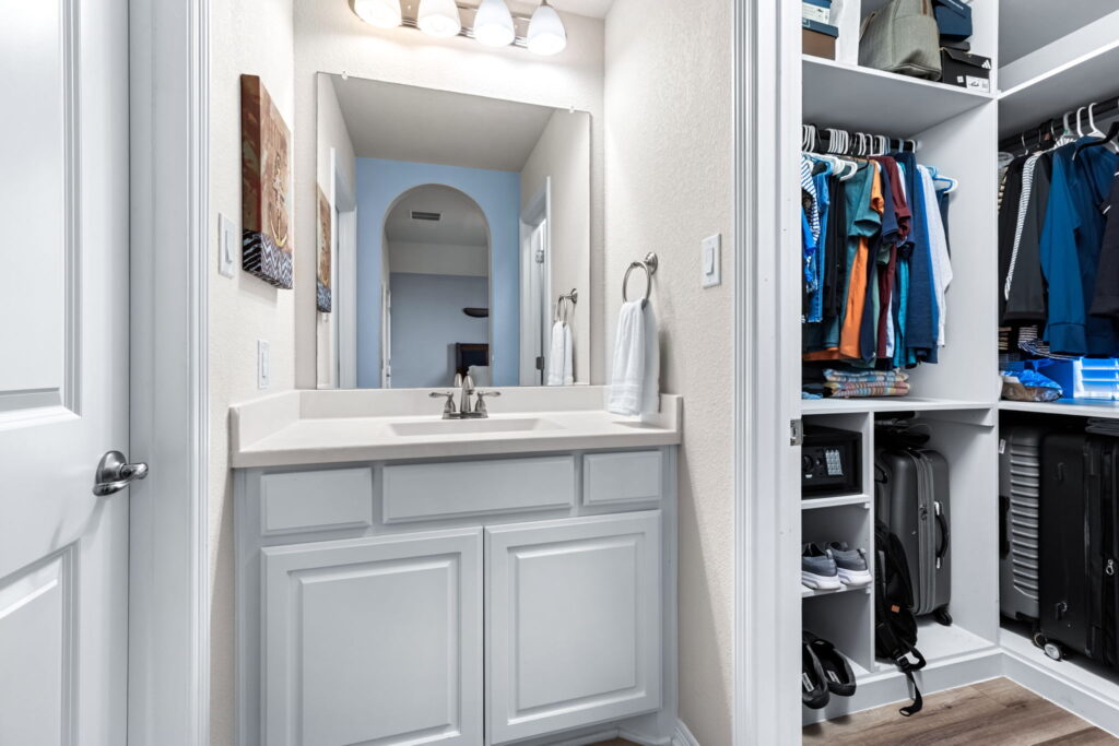 a modern residential bathroom vanity and fixtures and a walk in closet to the right