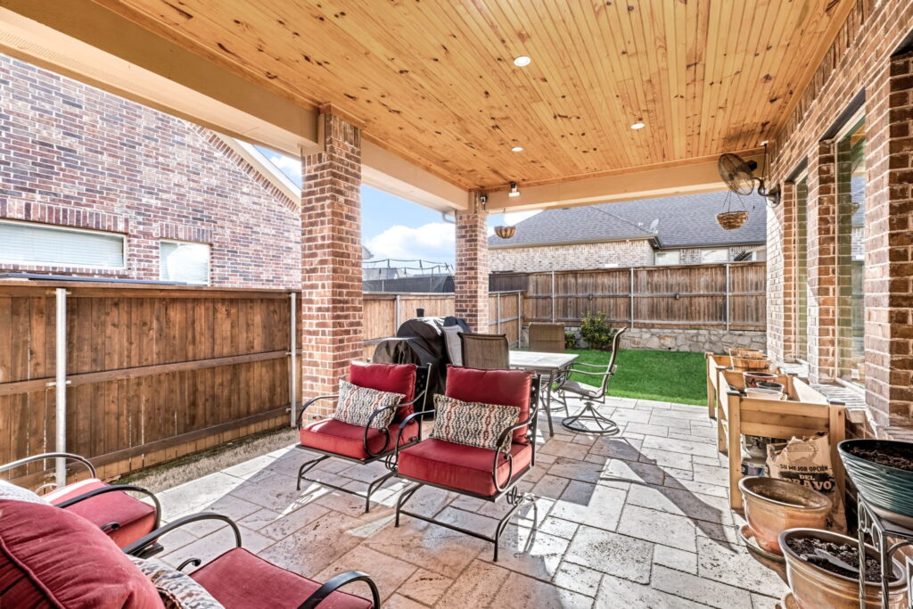 a modern covered outdoor patio furnished with red cushioned chairs and a dining table