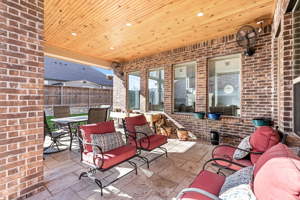 a modern covered outdoor patio furnished with red cushioned chairs and a dining table
