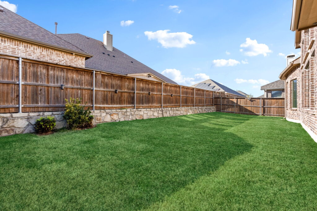 a backyard of a residential home, showcasing a manicured green lawn