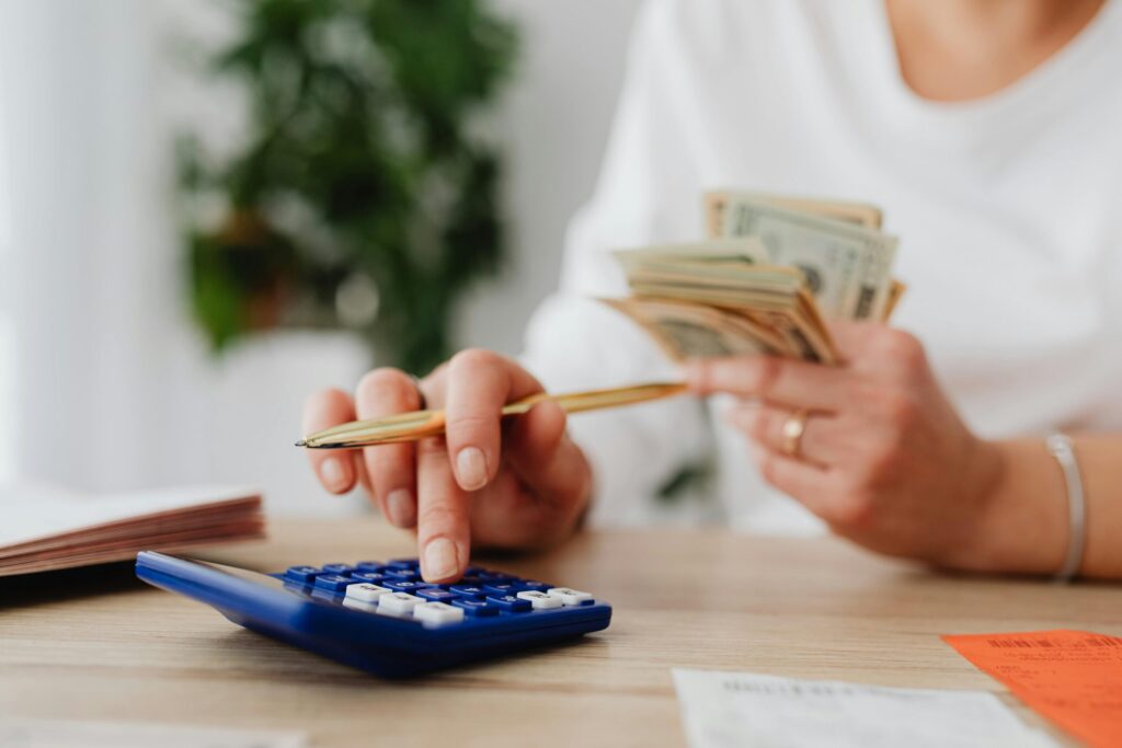 a person using a blue calculator and holding money on the other hand